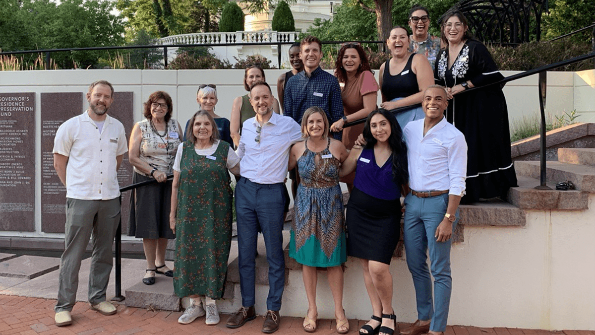 CCLP staff stand along and in front of the Governor's Mansion outdoor staircase, smiling.