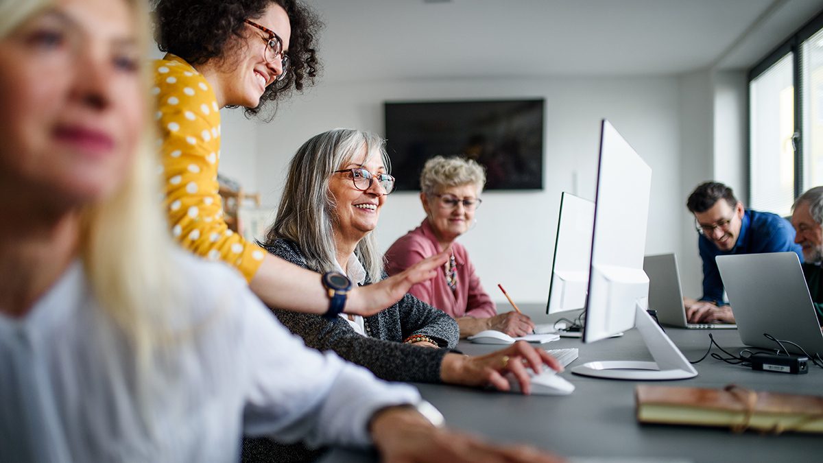 Group of cheerful senior people attending computer and technology education class.